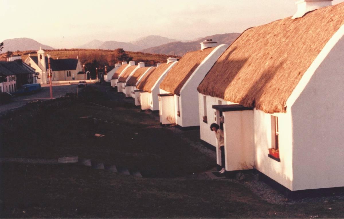 Tully Cross Cottages with thatched roofs in a long line at sunrise